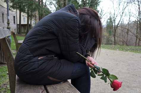 woman-sitting-on-bench-chair-holding-red-rose